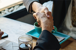 image of people shaking hands over coffee